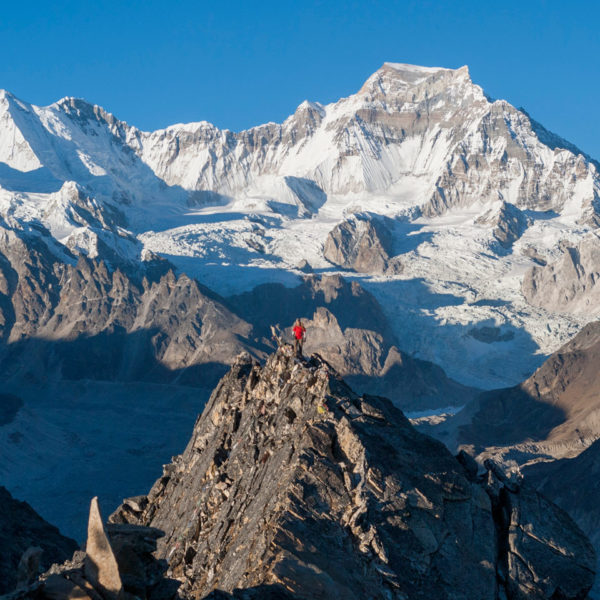 Trekker on top of Gokyo Ri with Mt Gyachung Kyang the worlds 15th highest mountain in the background